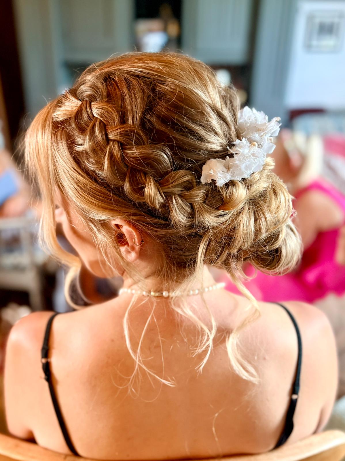 Intricate bridal updo with braided detail and floral accessory